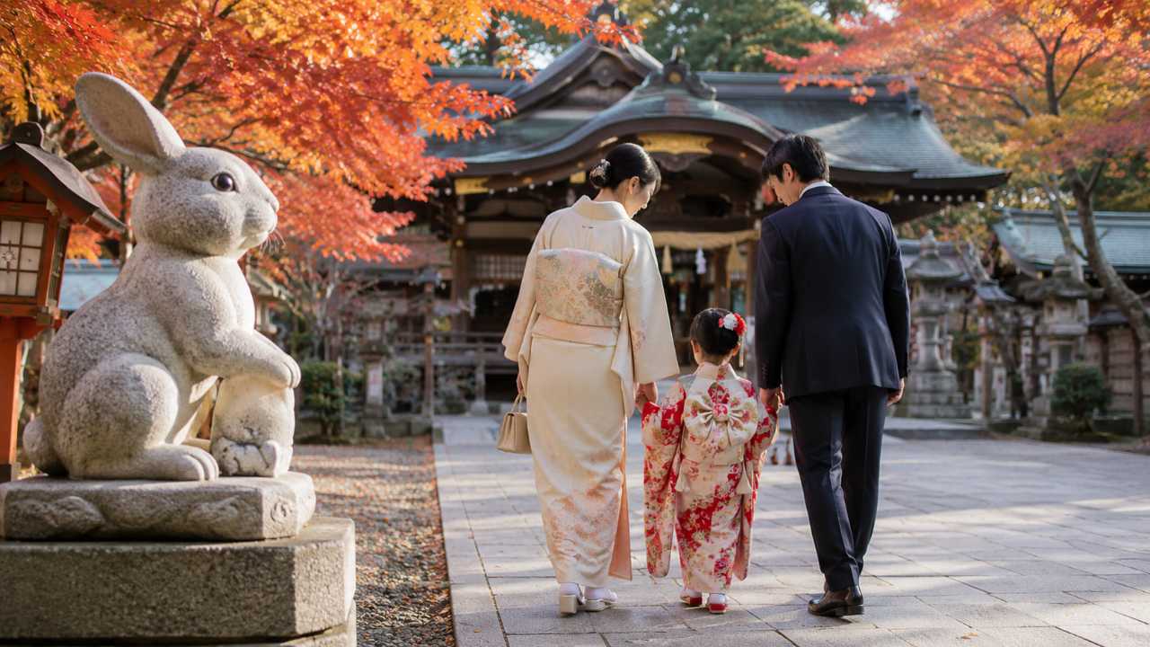 秋の柔らかい自然光、浦和の歴史ある神社の境内、狛兎を思わせる石像、七五三の着物を着た子どもと両親が穏やかに参拝している後ろ姿