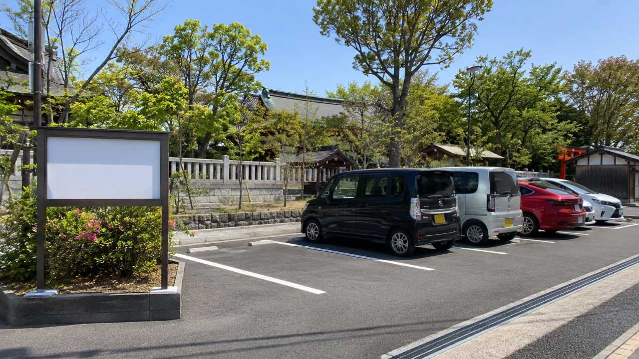 神社近くの駐車場をイメージした実写風画像。清潔な時間貸し駐車場に数台の車が停まり、奥に緑の多い神社周辺の雰囲気