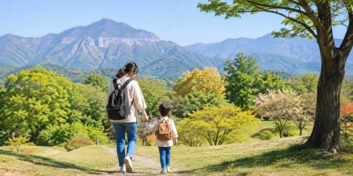 秩父の山並みと緑豊かな公園を背景に、親子が手をつないで歩いているブログ用アイキャッチ画像